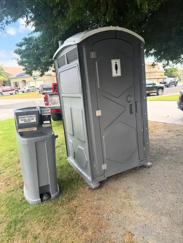 Porta potty with a hand-wash station beside it on a jobsite