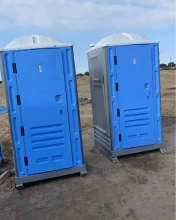 Two porta potties on a graded construction lot