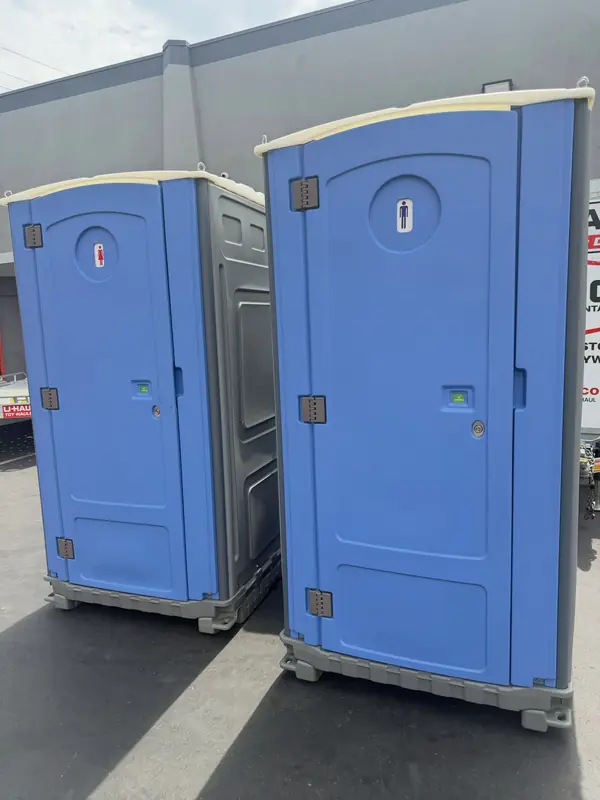 Two blue standard porta potties ready on pavement